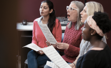 Choir members singling from sheet music